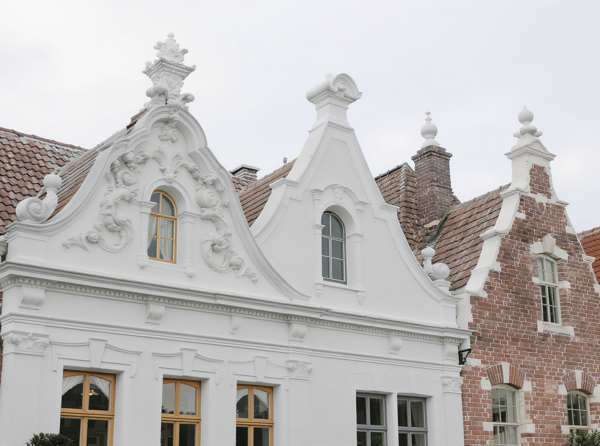 Detailed view of four different Cape Dutch gable types showing baroque, classical, bell, and stepped variations with traditional lime plaster finishes